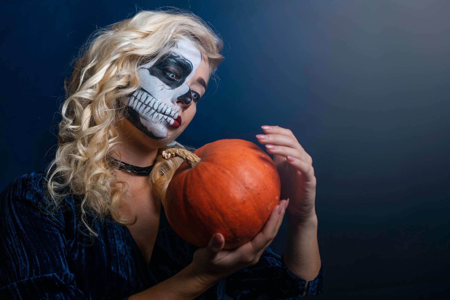 woman with face paint with pumpkin